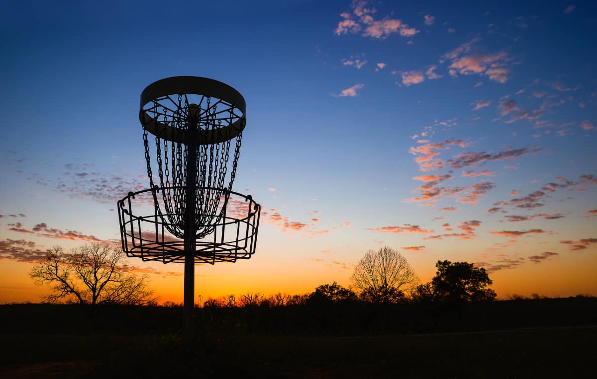 getting ready to play disc golf in Cincinnati; sunset behind a Disc Golf basket