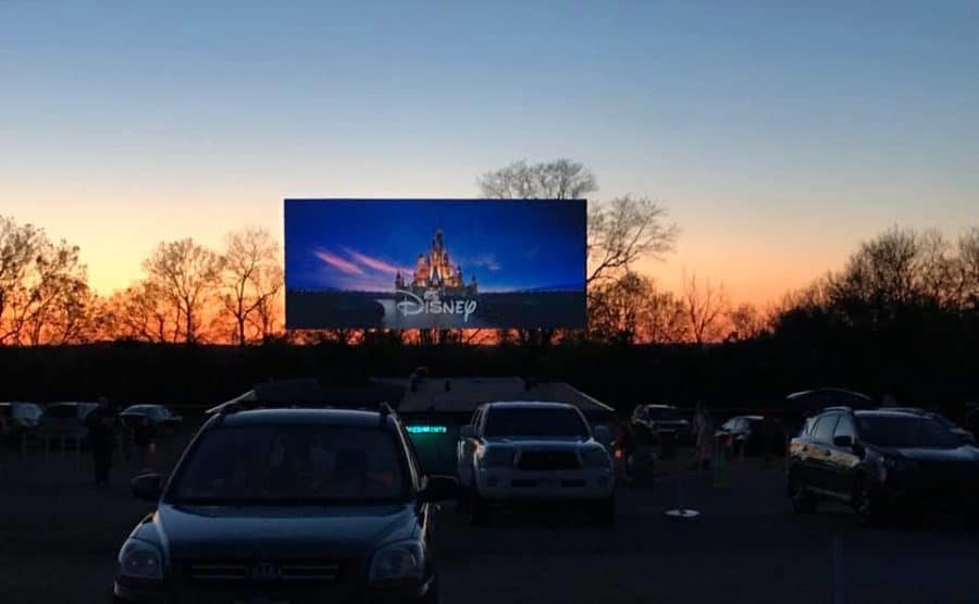 sunset behind a drive in movie theater sign with cars in the lot at Holiday Auto Theater in Hamilton, Ohio