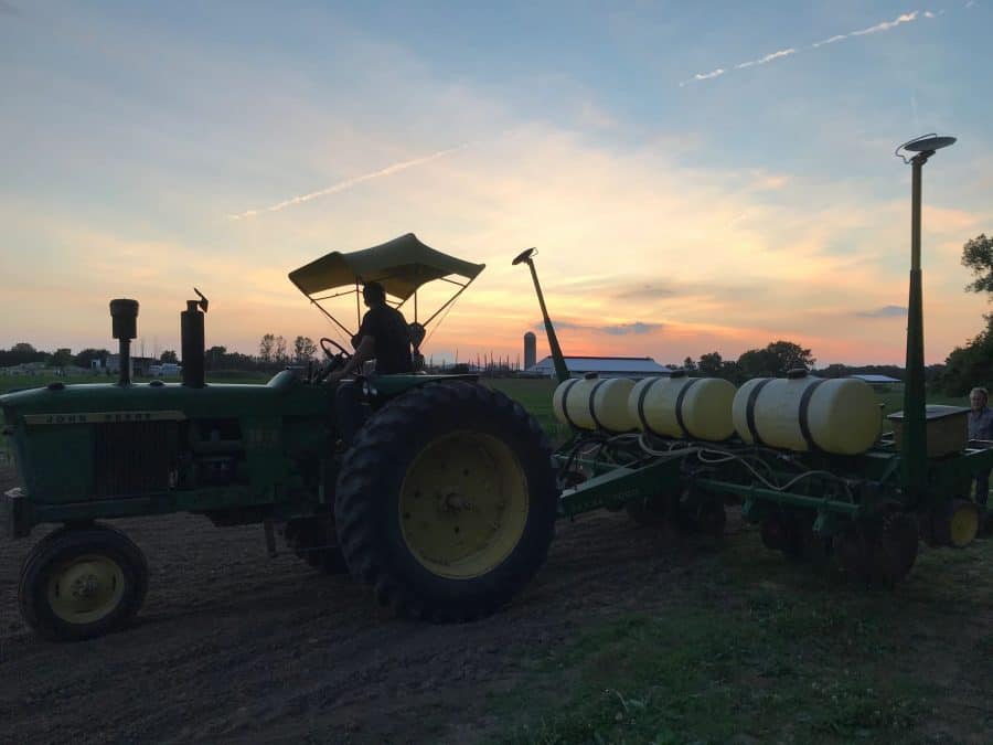 sunset view of the farmer on a tractor working in a field, planting at Niederman Family Farm