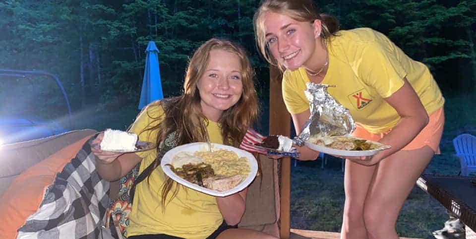 girls enjoying a meal over the fire at a campground