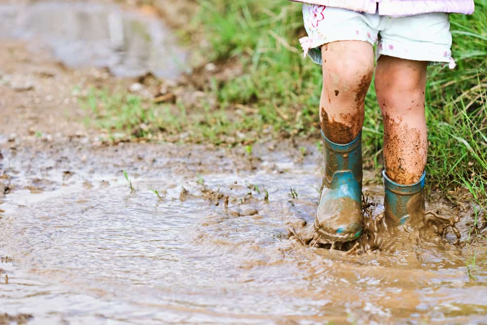 Child splashing in mud puddle