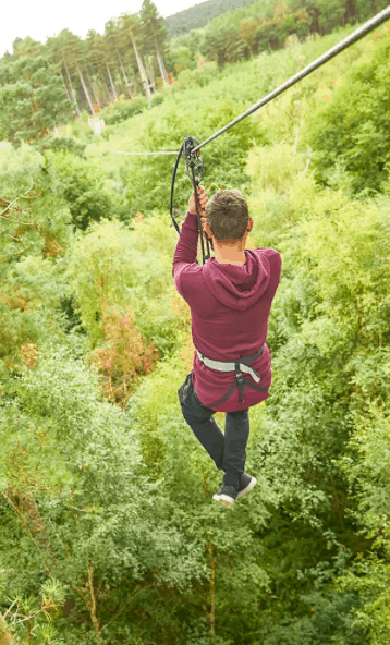 A man on a zip line going over trees
