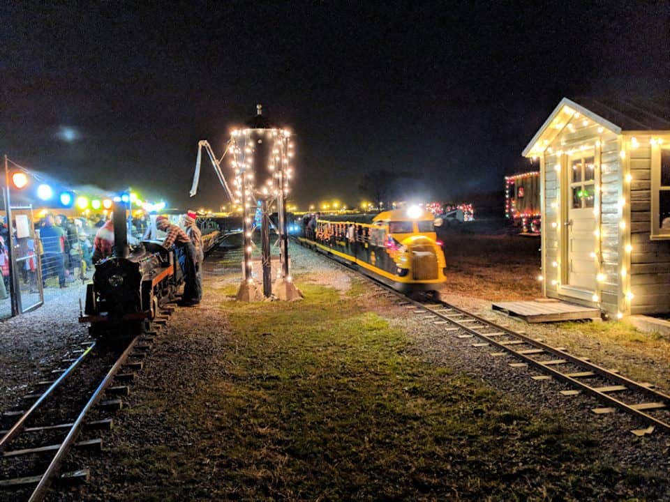 Small trains pulling into a town dressed for Christmas