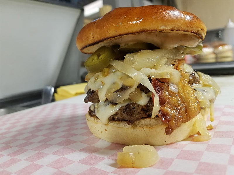 loaded burger on paper wrapper (photo credit to Bard's Burgers and Chili)