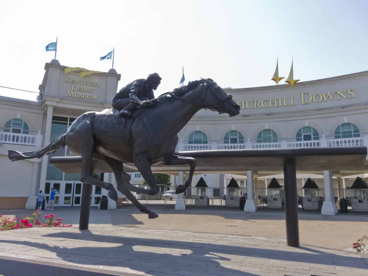 a horse and jockey statue in front of Louisville's Churchill Downs
