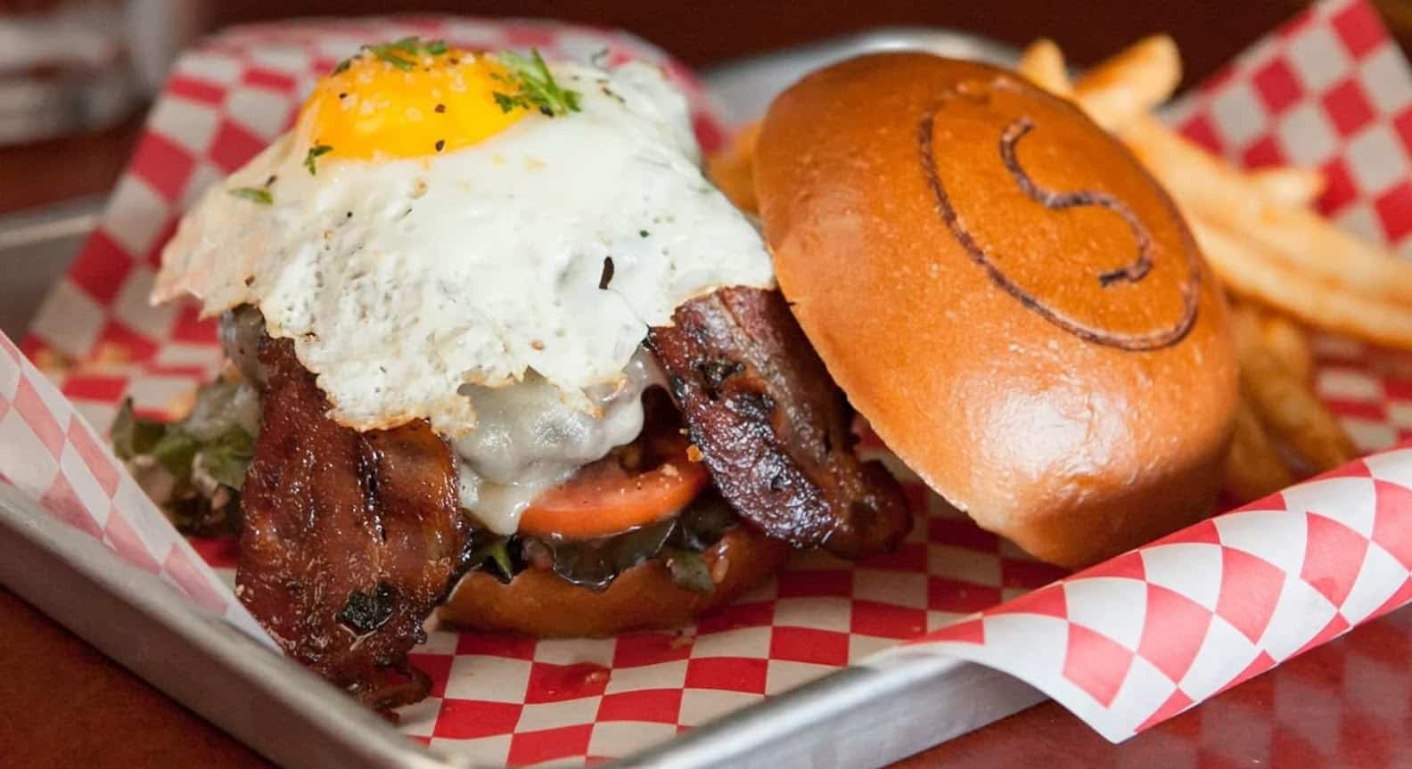 From our best burgers in Cincinnati list comes this burger topped with bacon and eggs, photo credit to Sammy's Craft Burgers