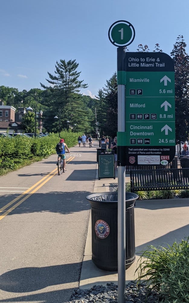 signage, bikes, and people along the Loveland Bike Trail in Cincinnati, Ohio