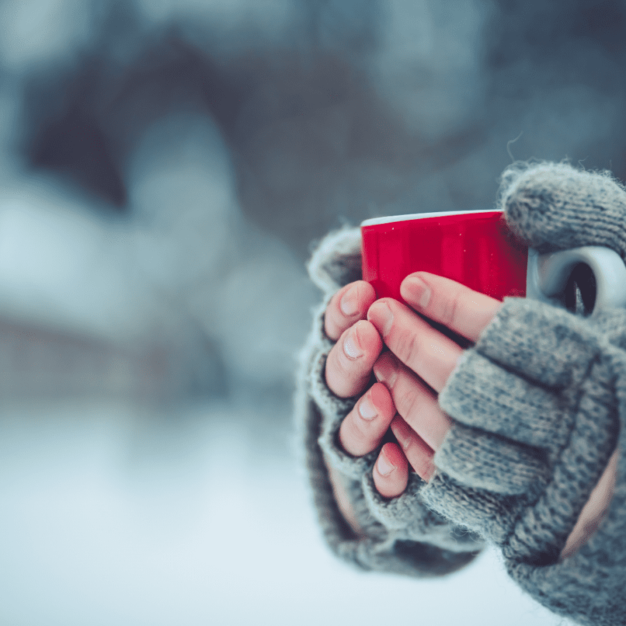 hands with mittens holding a mug