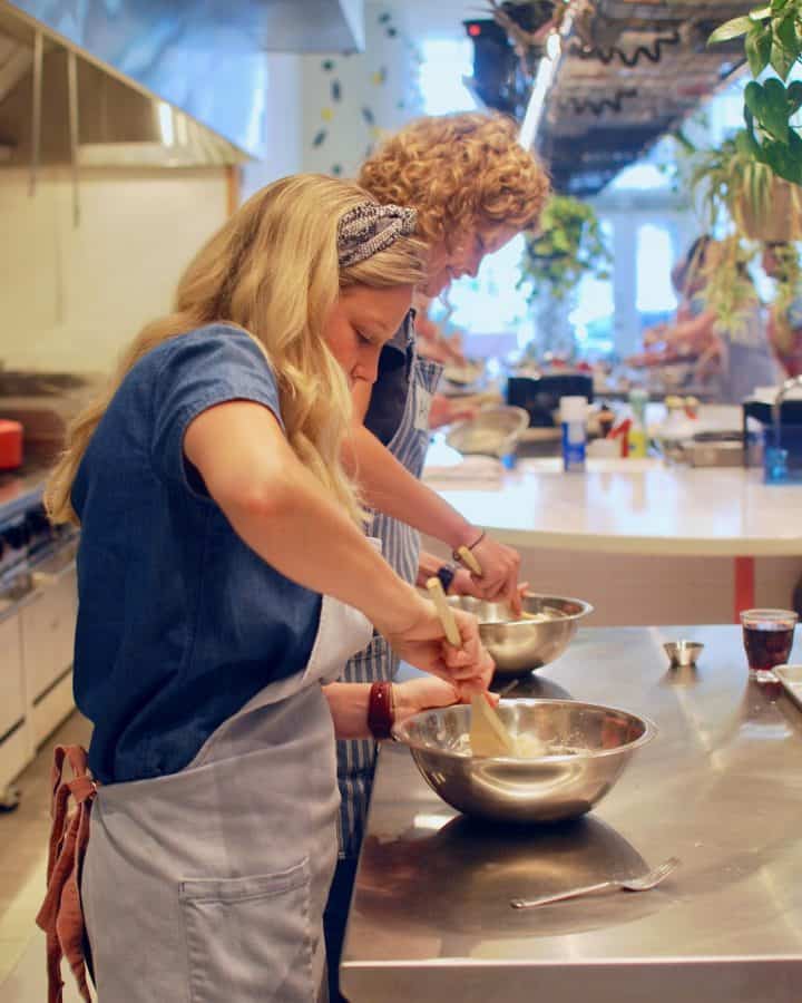 women stirring food in a bowl during a cooking class at Tablespoon Cooking Co