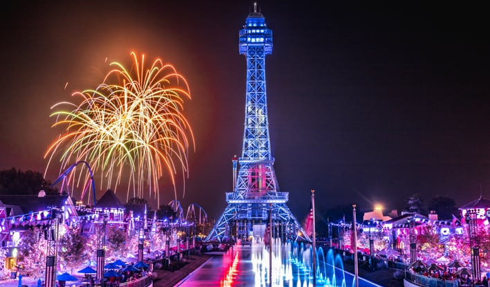 Kings Island at night featuring the Eiffel Tower, fireworks in the sky, the fountain and Main Street lights