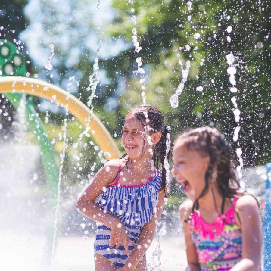 Girls playing at at splash pad in the summer