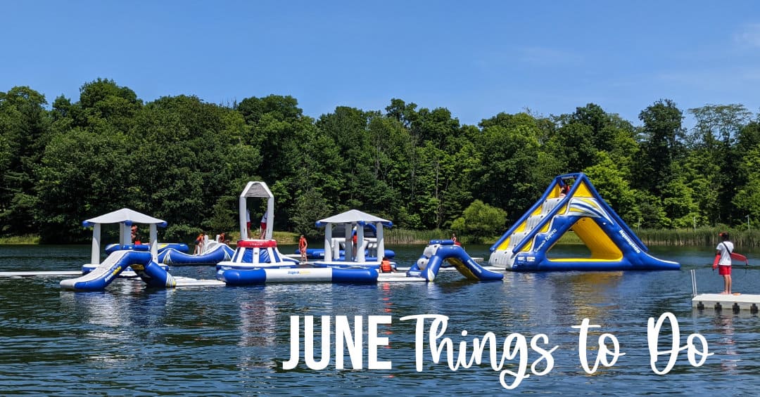 Kids playing on blow up obstacles in a lake