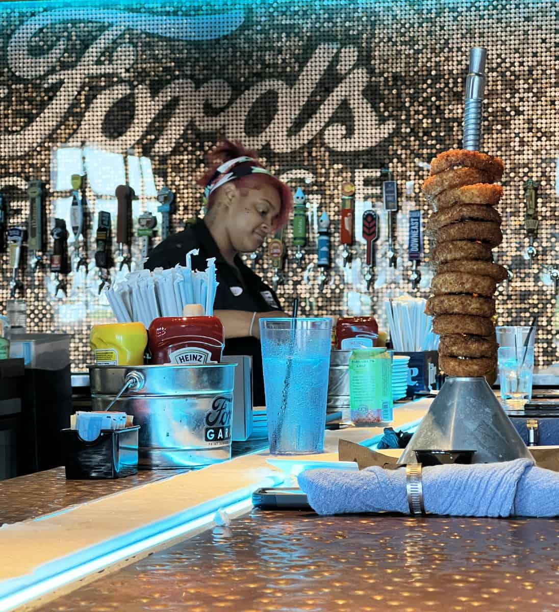 Bartender working at Ford's Garage in Cincinnati plus a giant stack of onion rings on an oil funnel