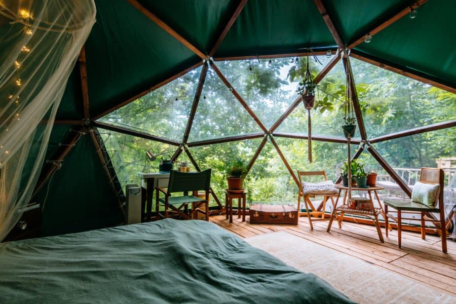 Glamping Dome set up with bed, chairs, desk and tables