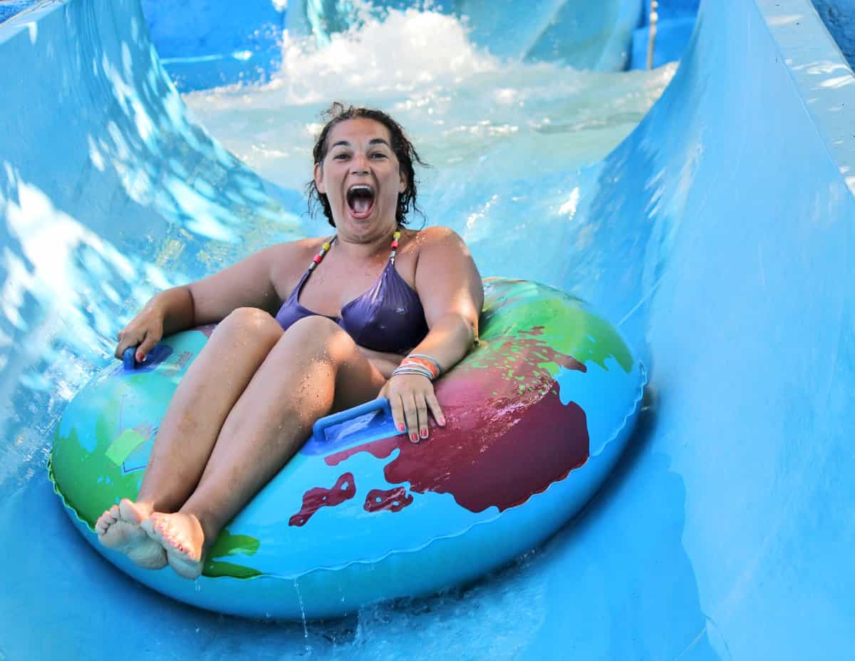 Woman on innertube going down a water slide at a waterpark

