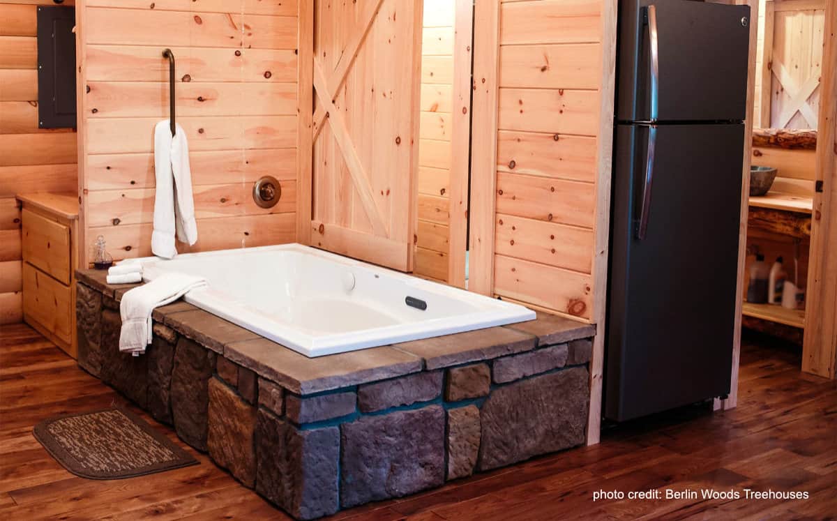 inside of a treehouse cabin with jetted tub and kitchen