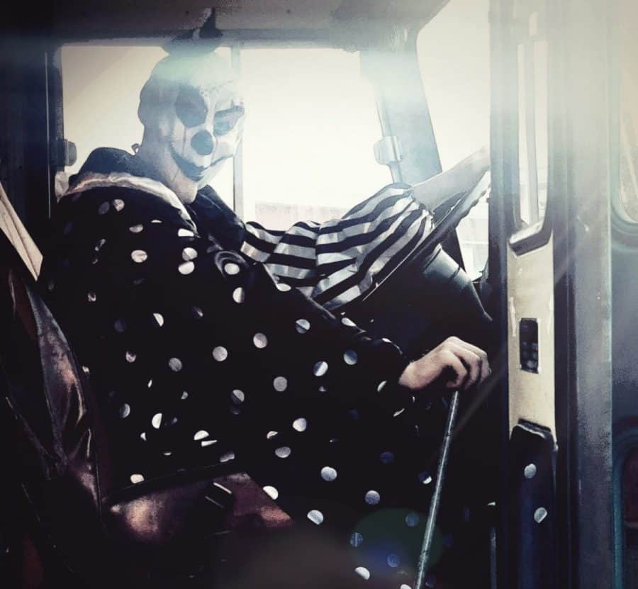 a clown from haunted houses sitting in the driver's seat of a school bus at Horror Hike 