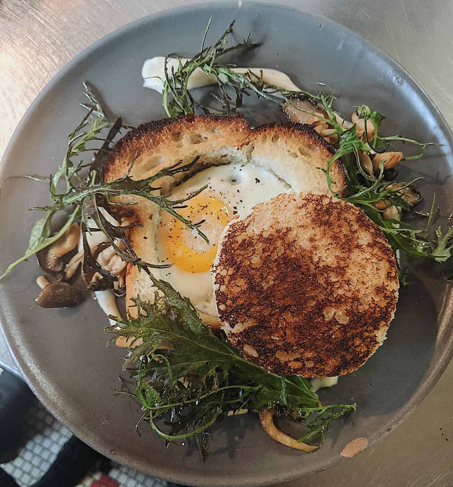 a breakfast plate with toast, eggs, and greens