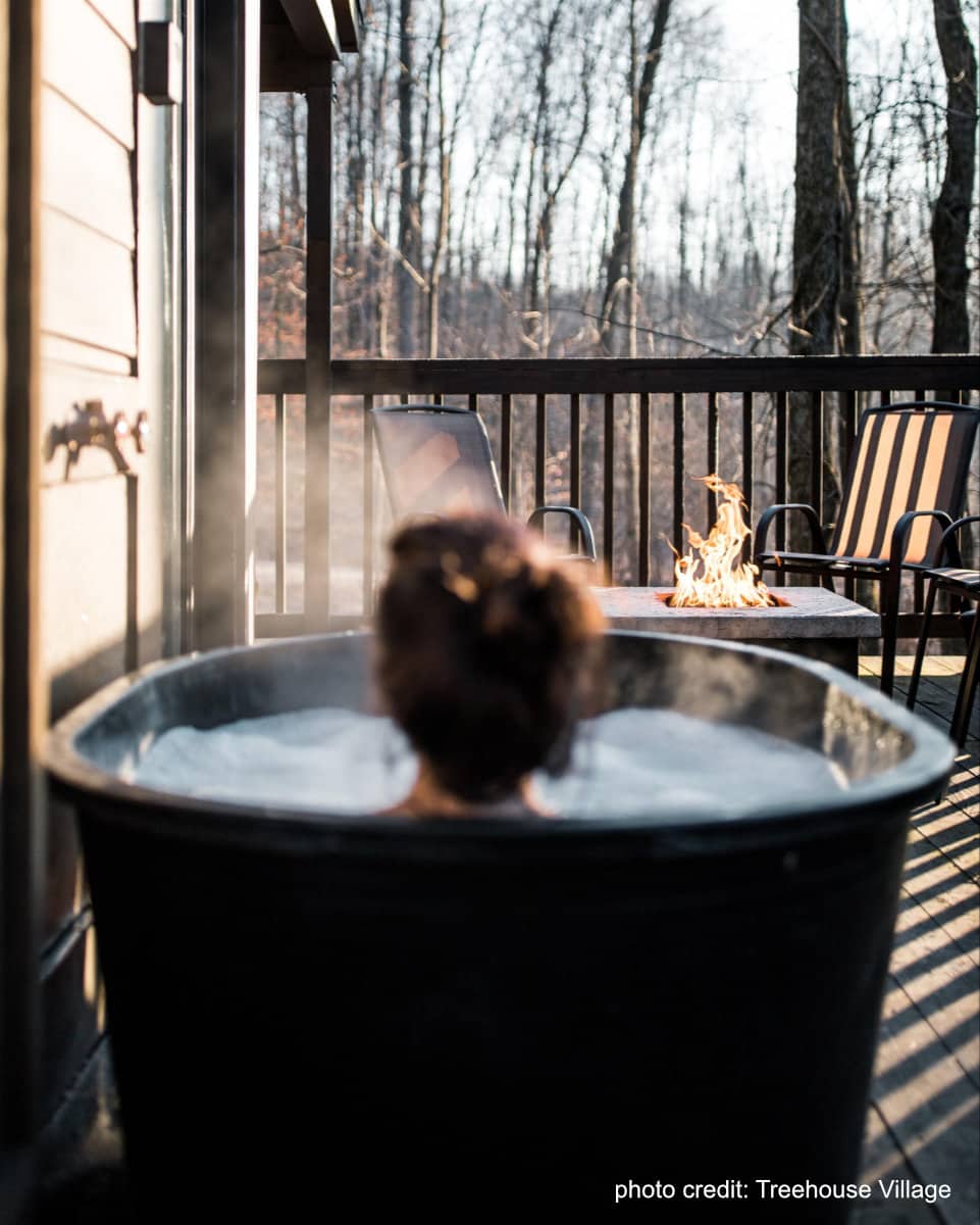 woman soaking in an outdoor tub at Treehouse Village in Dundee Ohio