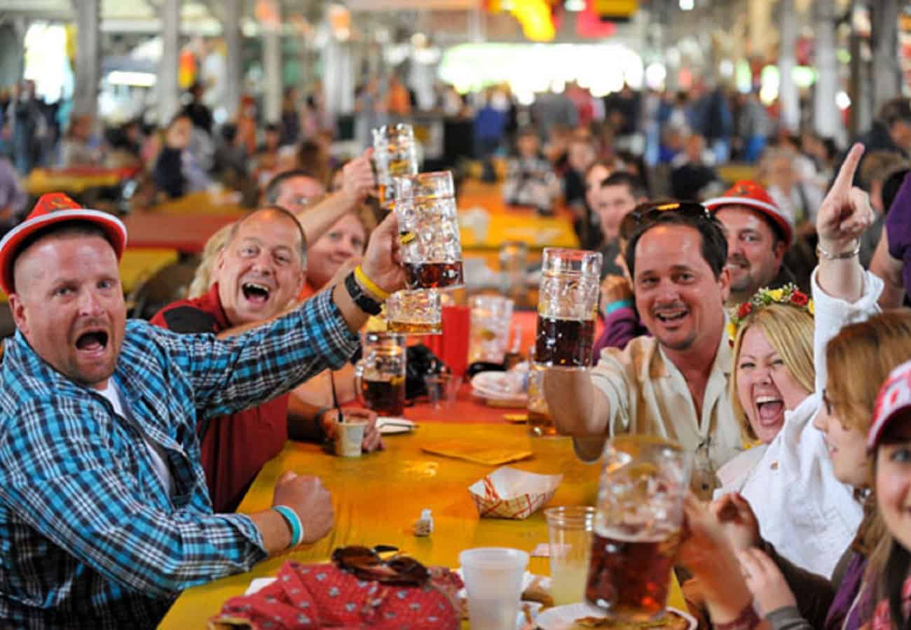 a crowd at an Oktoberfest celebration, raising beer steins