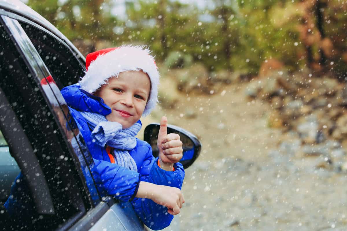 boy in blue coat in a car window used as the featured image in our list of best drive through Christmas lights in Ohio