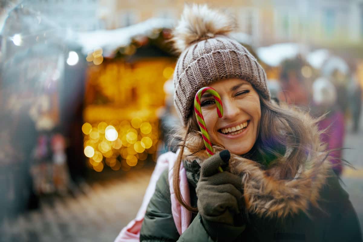 Woman dressed in hat and coat with candy cane and a smile