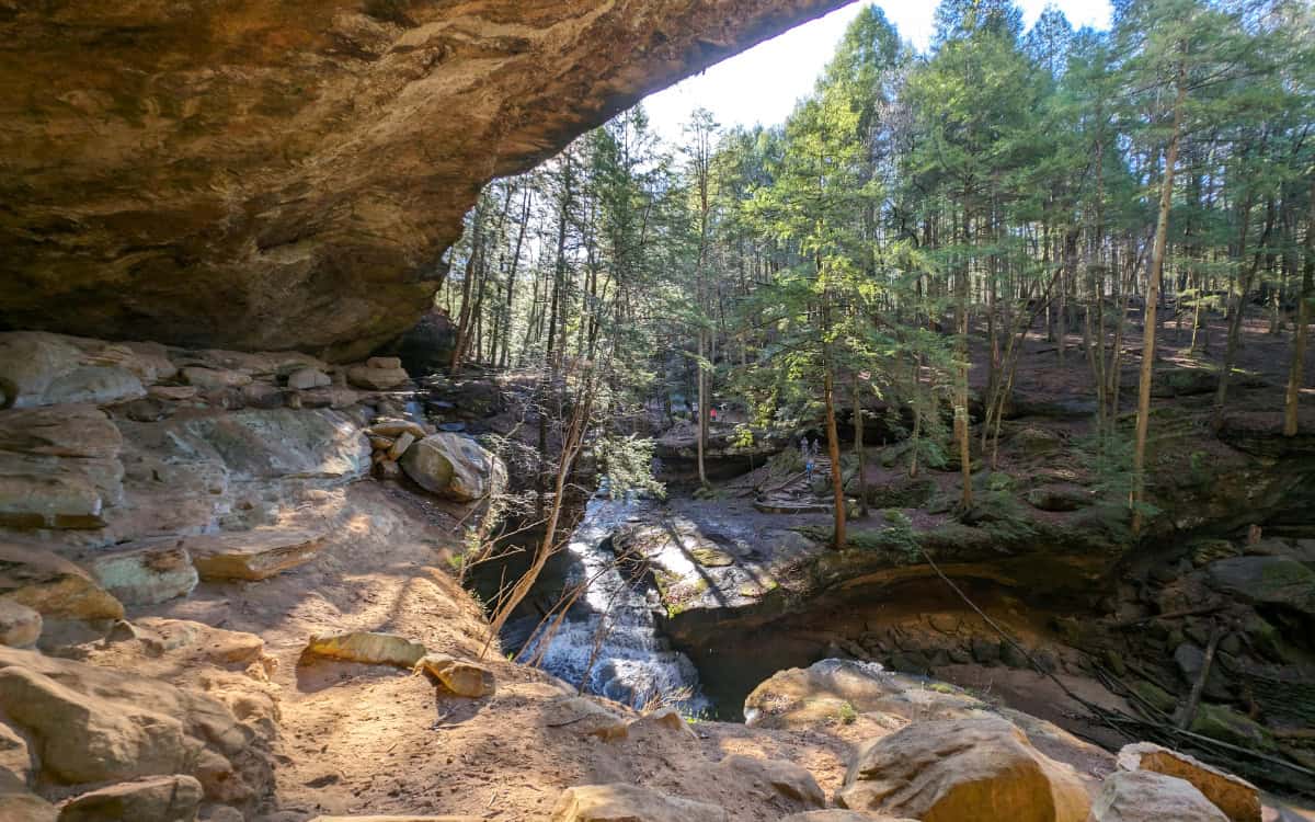 The view from a cave at Hocking Hills in Ohio. Looking out at the forest and a waterfall.