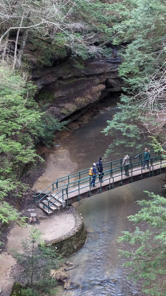 people traversing a bridge over a stream at Hocking Hills